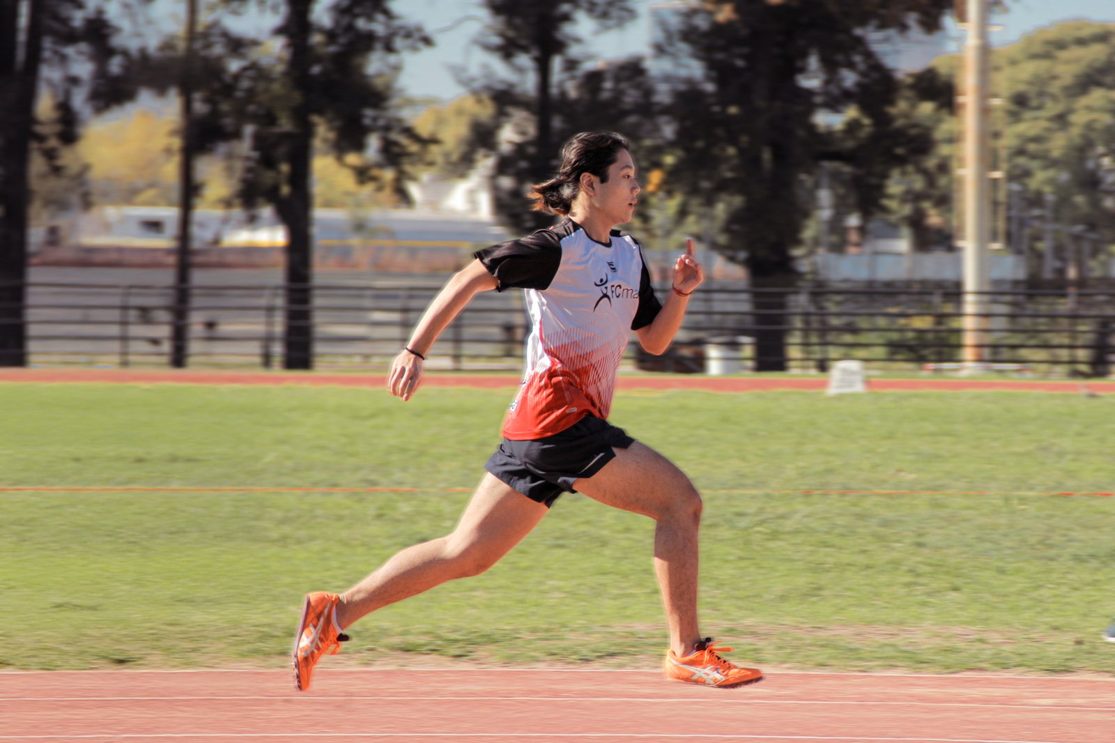 Atleta corriendo de perfil con calzado naranja